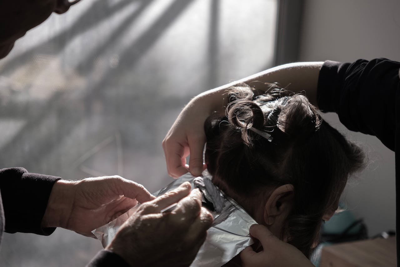 services-01 Expert hairdresser applying color highlights in a salon with natural lighting in İzmir, Türkiye.
